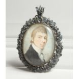 A GEORGIAN OVAL MINIATURE OF A YOUNG MAN, in a silver frame. 2.5ins x 2ins.