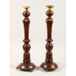 A PAIR OF GEORGIAN STYLE MAHOGANY CANDLESTICKS on circular bases. 17ins high.