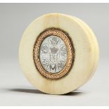 A GEORGIAN IVORY CIRCULAR BOX, the top with an oval crest. 2.25ins diameter.