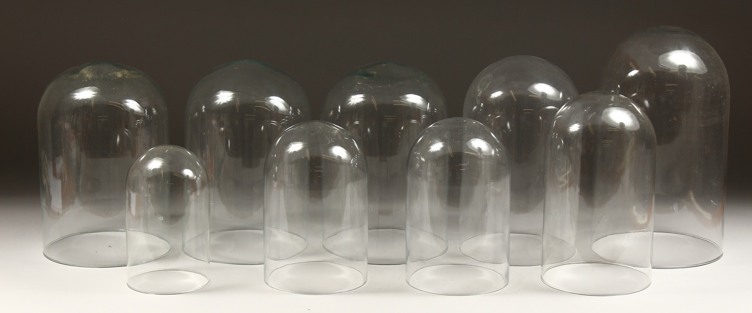 A COLLECTION OF 9 GLASS DOMES. 14ins to 8ins high.