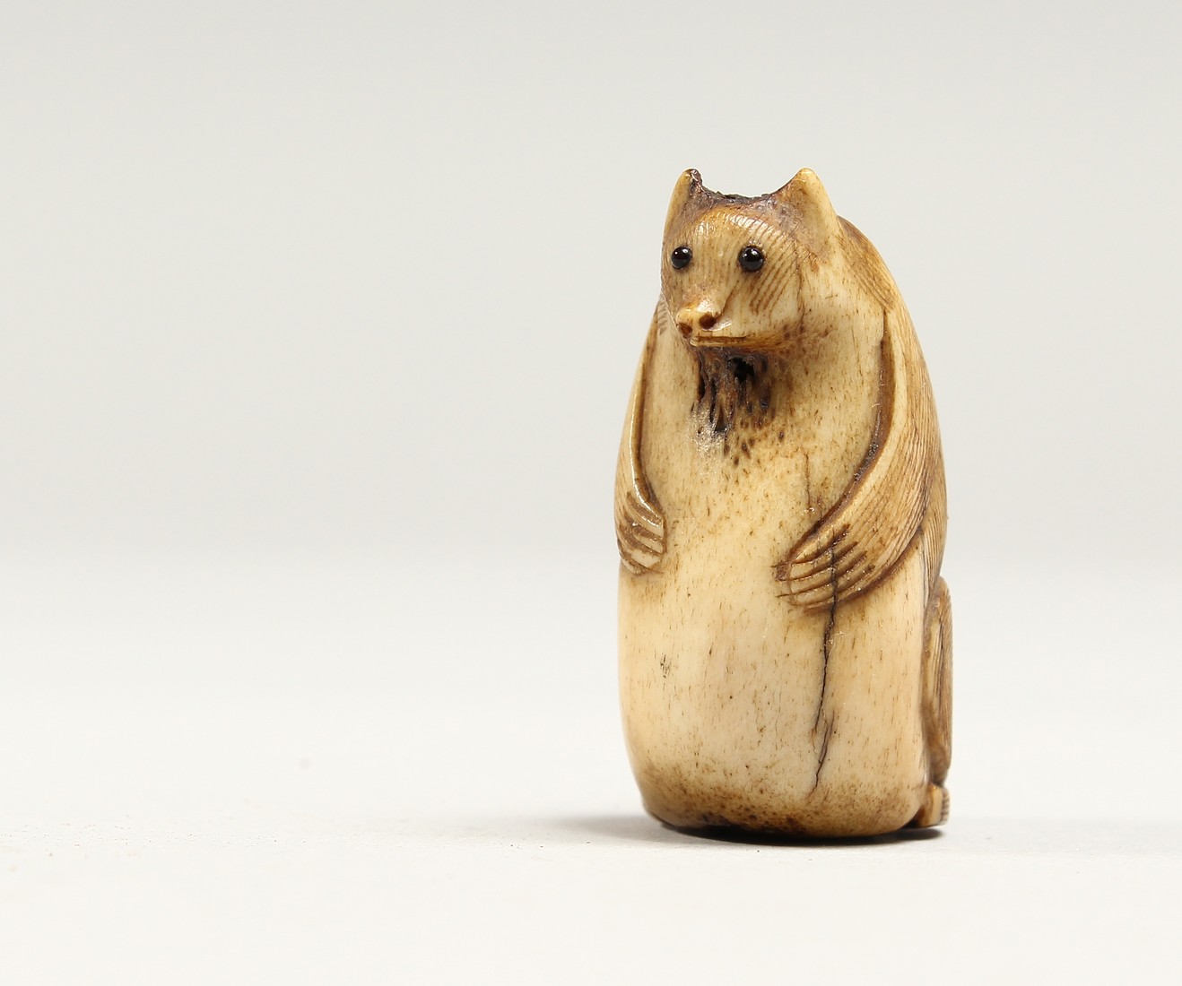 A CARVED BONE NETSUKE OF A BEAR 1.25ins