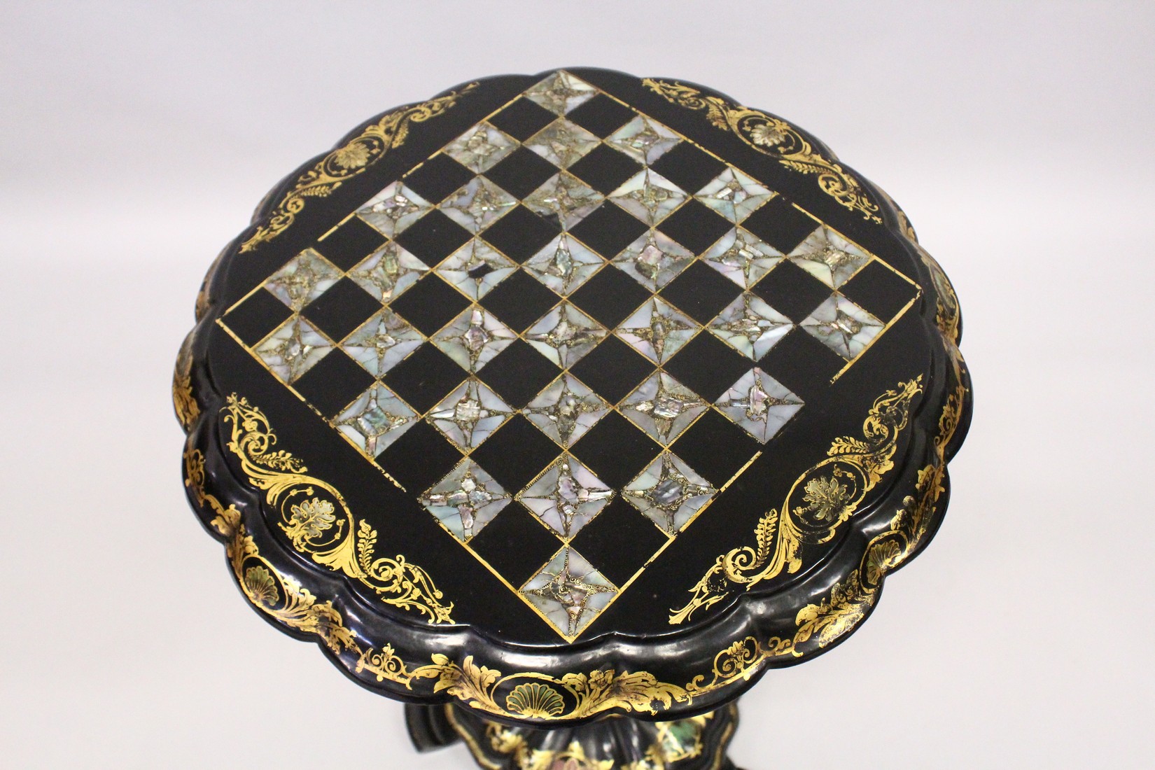 A VICTORIAN BLACK AND GILT PAPIER MACHE TILT TOP GAMES TABLE, with inlaid chess board in mother of - Image 2 of 5