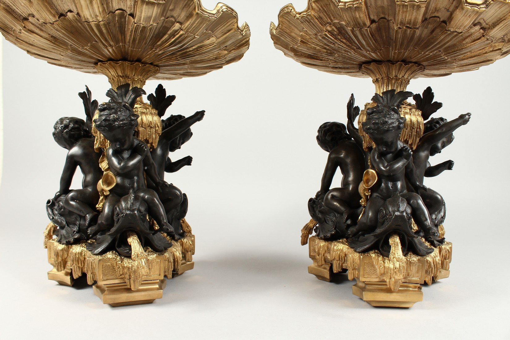 A GOOD PAIR OF BRONZE AND GILT BRONZE COMPORTS with shell shaped tops, three cupid supports. 13ins - Image 5 of 5