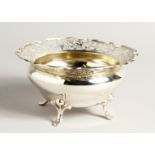 A CIRCULAR SILVER PIERCED BOWL on four curving legs 6ins diameter, maker James & William Dixon.