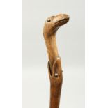 A RUSTIC WOODEN WALKING STICK, a snake eating a bird. 33ins long.