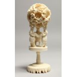 A FAUX IVORY PUZZLE BALL on a stand. 7ins high