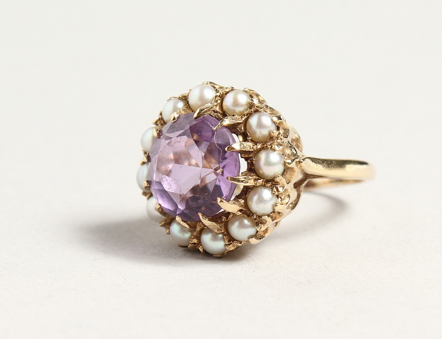 A GOLD CIRCULAR AMETHYST AND PERAL CLUSTER RING