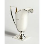 A HELMET-SHAPED SILVER CREAM JUG on a square base. Birmingham 1908. 12cm tall - 78g