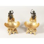 A PAIR OF ORMOLU AND BRONZE CUPID SALTS 7ins high.