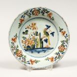 A GOOD ENGLISH DELFT CIRCULAR TIN GLAZED PLATE, flowers and a brilliant coloured bird. 8.75ins