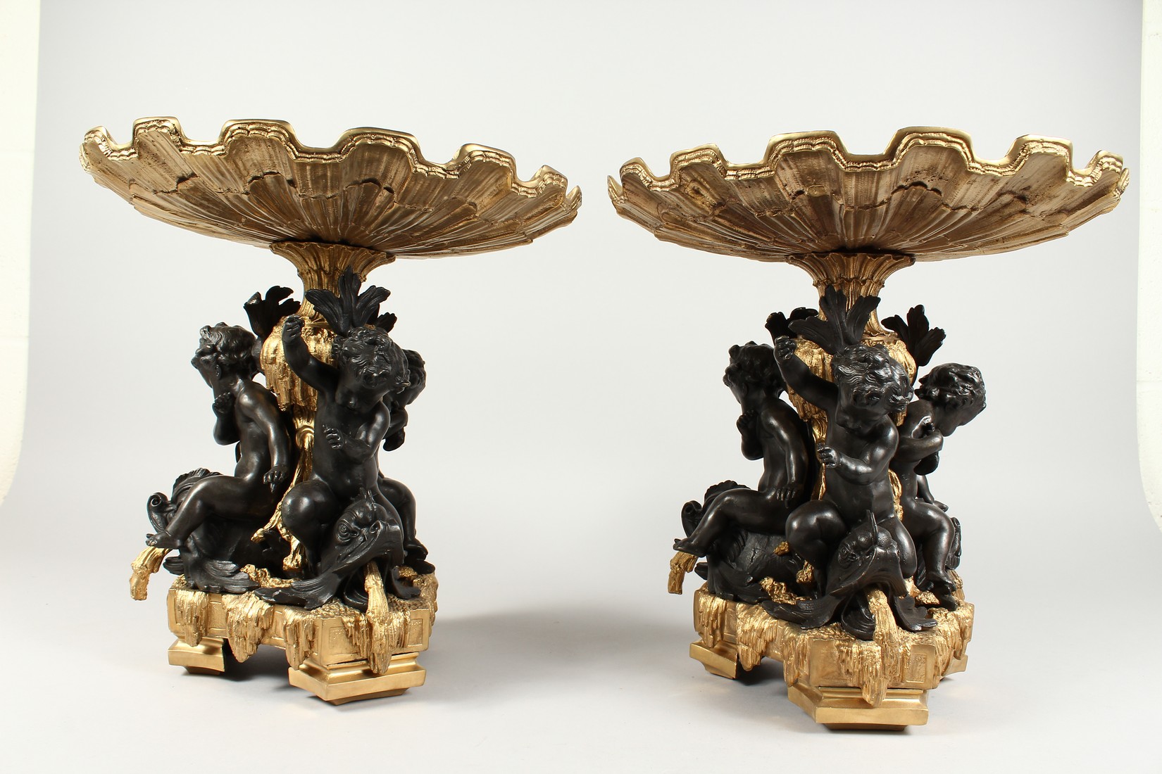 A GOOD PAIR OF BRONZE AND GILT BRONZE COMPORTS with shell shaped tops, three cupid supports. 13ins - Image 3 of 5