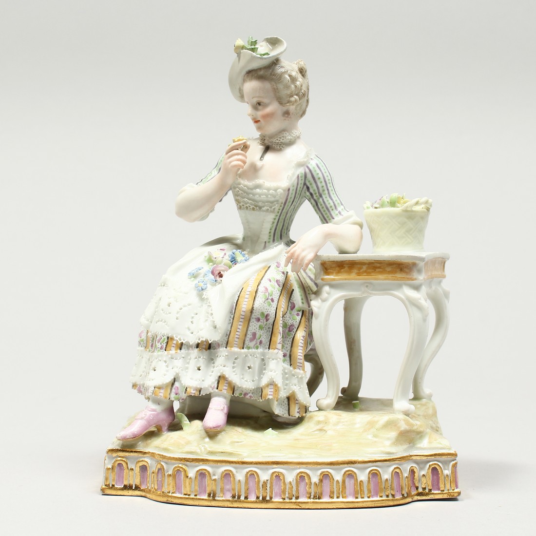 A GOOD MEISSEN PORCELAIN GROUP 'SENSE AND SMELL', a young lady sitting beside a table smelling