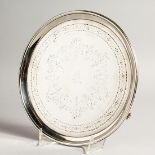 A GEORGE III SILVER CIRCULAR ENGRAVED SALVER with crest, on three curving legs. 8ins diameter,