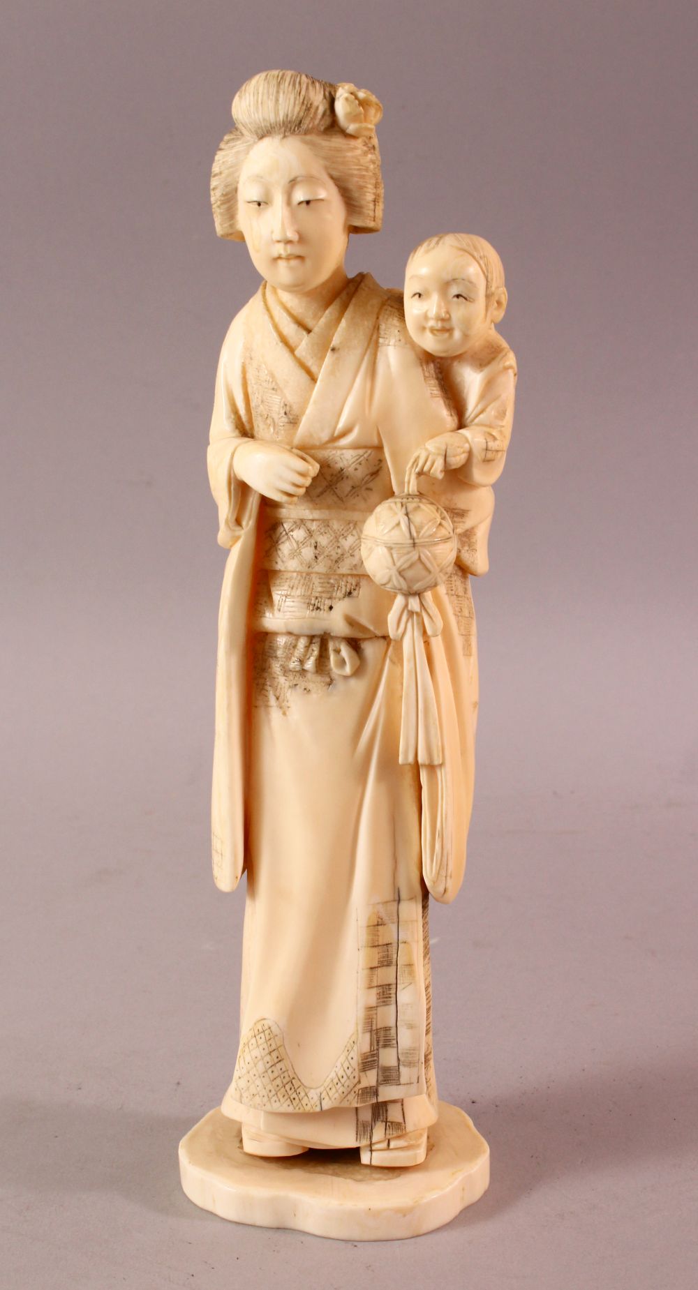 A LARGE JAPANESE MEIJI PERIOD CARVED IVORY OKIMONO - MOTHER AND CHILD, the mother stood holding