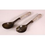 AN ASIAN CARVED RHINO HORN & WHITE METAL SERVING SET, comprising two items formed of horn with