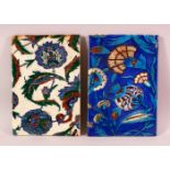 TWO IZNIK STYLE POTTERY TILES, with blue and white grounds with floral decoration, 23.5cm x 26cm.