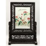 A CHINESE PORCELAIN SCREEN, with flowers and calligraphy, 14ins x 9.5ins on a wooden stand.