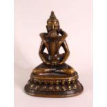 A TIBETAN GILT BRONZE FIGURE OF SEATED buddha and figure, in a semi erotic pose with a vessel,