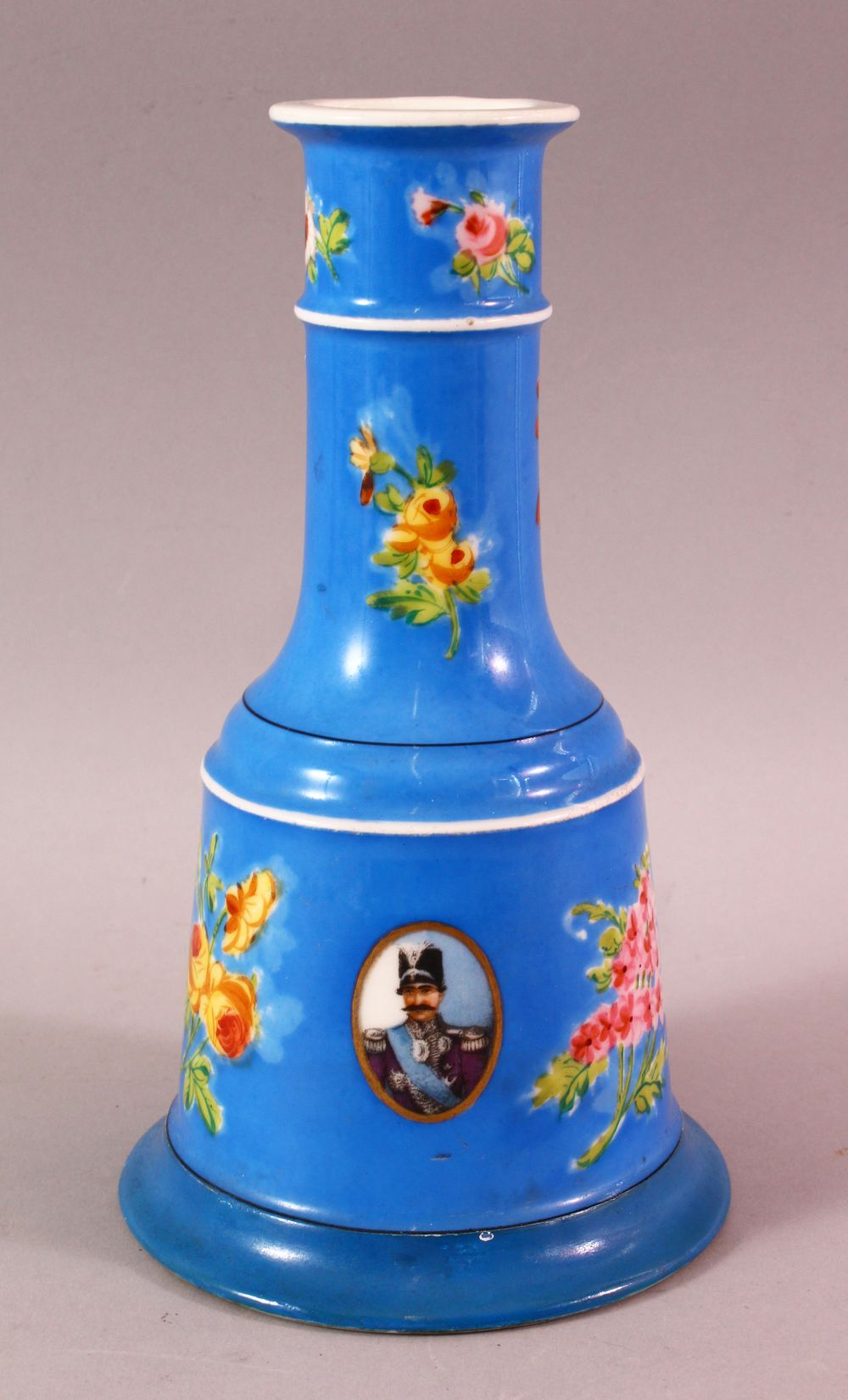 A PERSIAN QAJAR PORCELAIN HUQQA BASE, with ablue ground and figural decoration around flora, 23cm