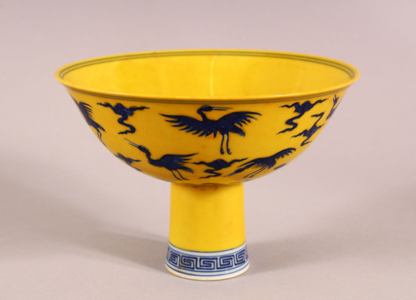 A CHINESE YELLOW GROUND PORCELAIN STEM CUP, decorated with cranes in flight, the interior of the