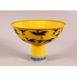 A CHINESE YELLOW GROUND PORCELAIN STEM CUP, decorated with cranes in flight, the interior of the
