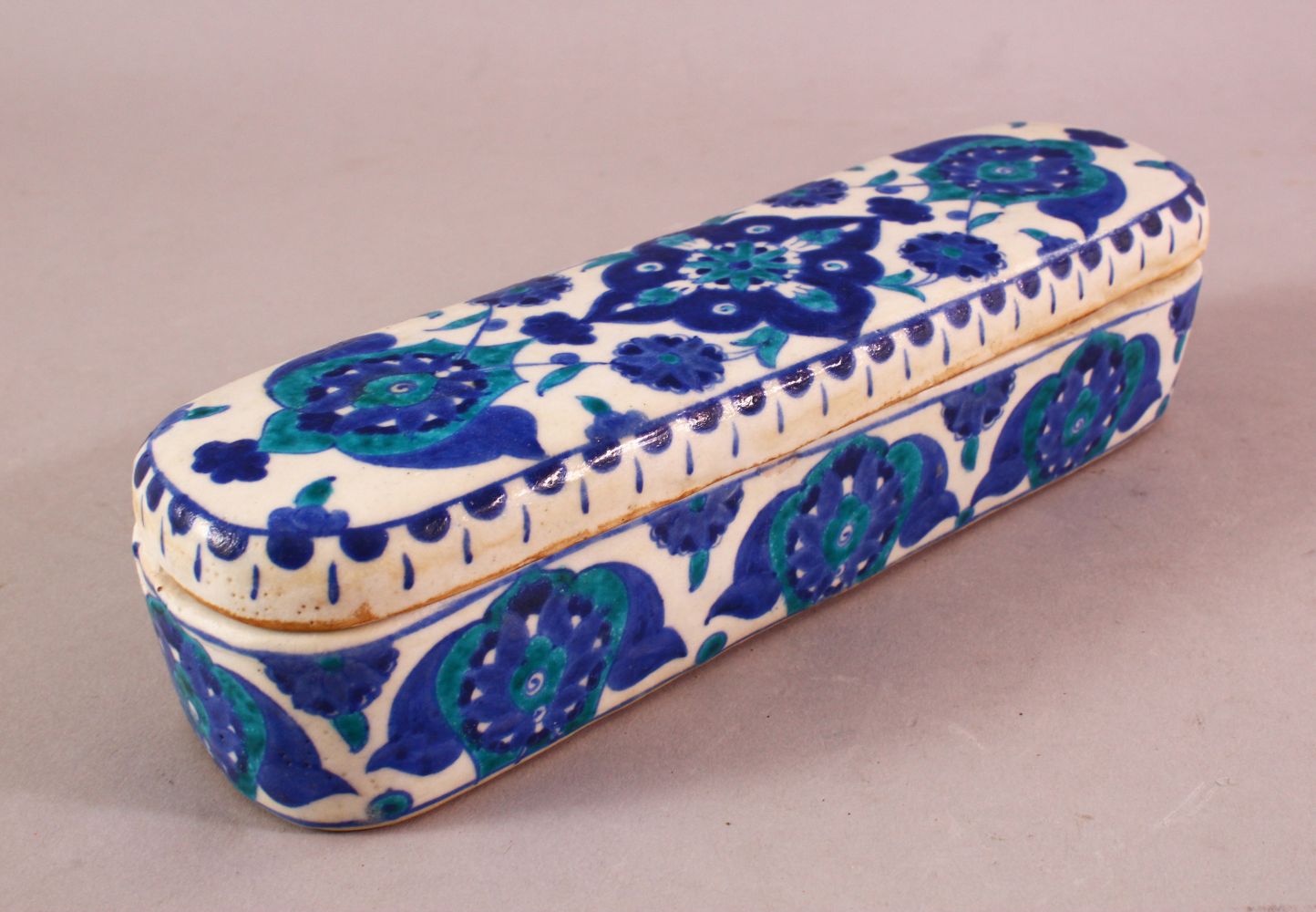 A TURKISH OTTOMAN KUTAHYA POTTERY PEN BOX & COVER, in blue and white floral decoration, 23cm