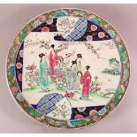 A LARGE JAPANESE POLYCHROME PORCELAIN CHARGER, depicting females in a garden setting, the