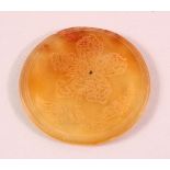 AN ISLAMIC CIRCULAR YELLOW AGATE PLAQUE, with engraved decoration, 6cm diameter.