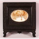 A GOOD INDIAN CARVED EBONY & PAINTED frame, the frame carved with native foliage, the centre with