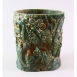 A CHINESE GREEN HARDSTONE BRUSH POT, carved with figures and trees, calligraphy, 15.5cm high.