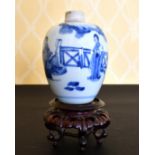 A KANG HSI BLUE AND WHITE VASE painted with figures and fence. 6ins high, on a wooden stand.