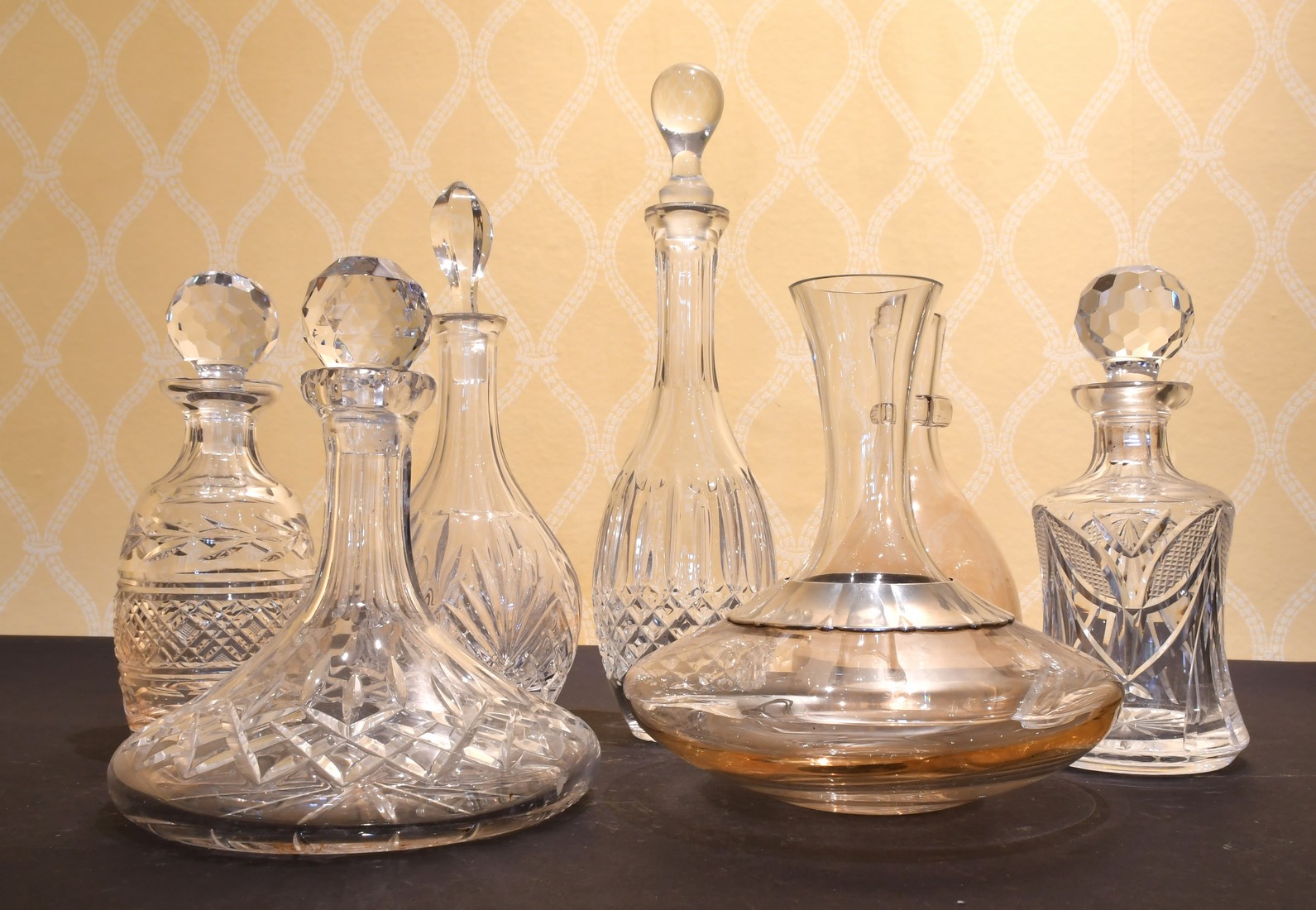 A CUT GLASS SHIPS DECANTER AND STOPPER AND SIX OTHER DECANTERS.