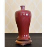 A CHINESE PINKY RED VASE AND STAND. 9ins high.