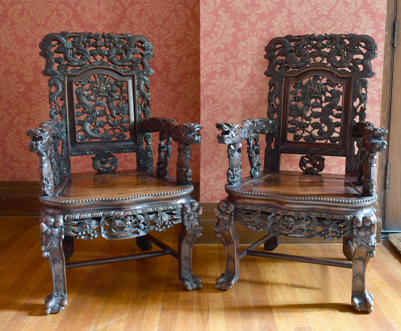 A GOOD PAIR OF CHINESE CARVED AND PIERCED ARMCHAIRS with solid seats, dragon arms and foliage.