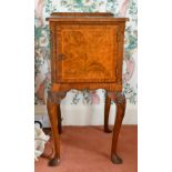 A FIGURED WALNUT BEDSIDE CUPBOARD with panel doors, on cabriole legs.