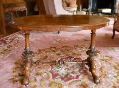 A VICTORIAN OVAL WALNUT STRETCHER TABLE with turned supports, curving legs with white porcelain