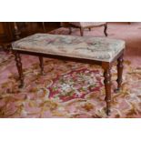 A LONG VICTORIAN PIANO STOOL with tapestry top, on turned legs with porcelain castors. 3ft long.