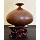 A GOOD HEAVY CARVED WOOD VASE on a stand.