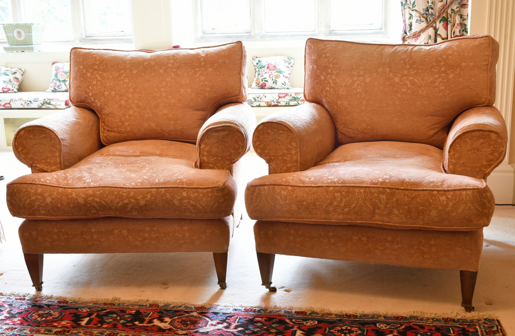 A GOOD PAIR OF LARGE DEEP EASY ARMCHAIRS on tapering legs with brass castors.