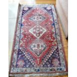 A PERSIAN WOOL RUG with three central medallions. 5ft 6ins x 2ft 9ins.