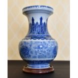 A LARGE CHINESE BLUE AND WHITE VASE with a band of flowers. 14ins high, on a wooden stand.