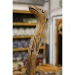 A folk art walking stick modelled as a snake eating a bird