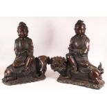 A PAIR OF CHINESE CAST BRONZE FIGURES OF GUANYIN SEATED UPON LION DOGS, Each impressed to the