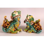 A PAIR OF 20TH CENTURY CHINESE SANCAI POTTERY LION DOGS - the mirrored pair both looking on - one