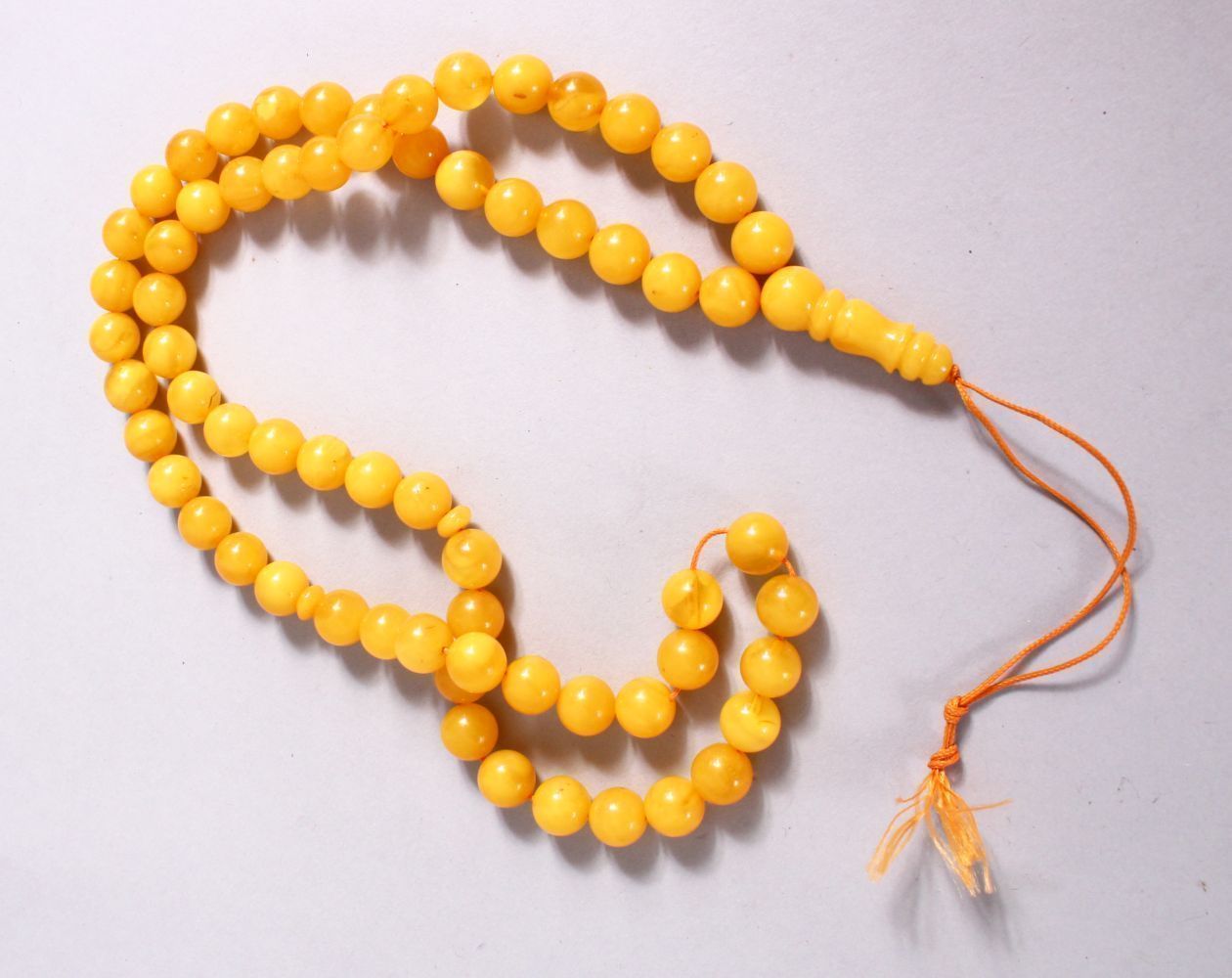 A CHINESE QING DYNASTY CARVED AMBER PRAYER BEADS / ROSARY NECKLACE, comprising 66 beads, 3 spacers