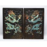 A PAIR OF CHINESE CARVED AND PAINTED HARDWOOD PANELS, depicting dragons each holding the pearl of