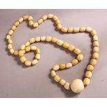 A LONG IVORY BEAD NECKLACE, comprising 62 barrel shaped beads and a large central bead: 25mm wide,