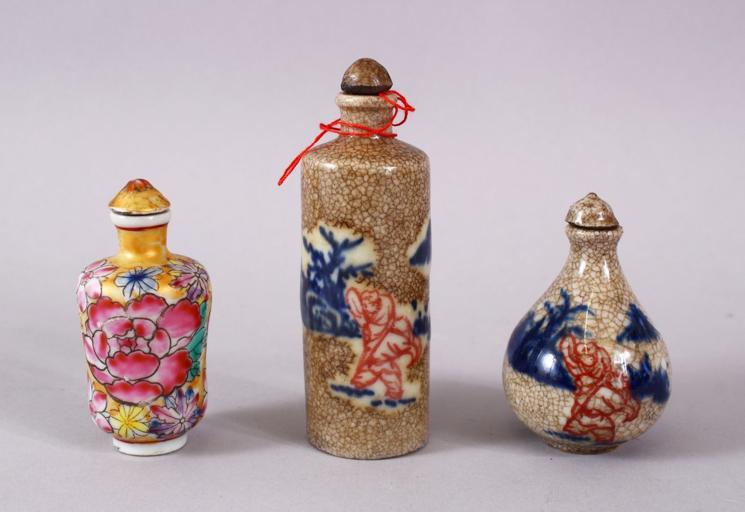 THREE CHINESE PORCELAIN SNUFF BOTTLES, one of floral design, the other two with underglaze blue