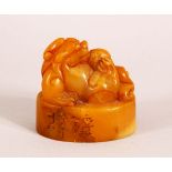 A CHINESE CARVED AMBER COLOUR SOAPSTONE SEAL OF A LION DOG - the dog on its back , the base carved