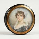 A GEORGIAN EBONY CIRCULAR BOX, the top painted with a portrait of a young lady wearing pearls.